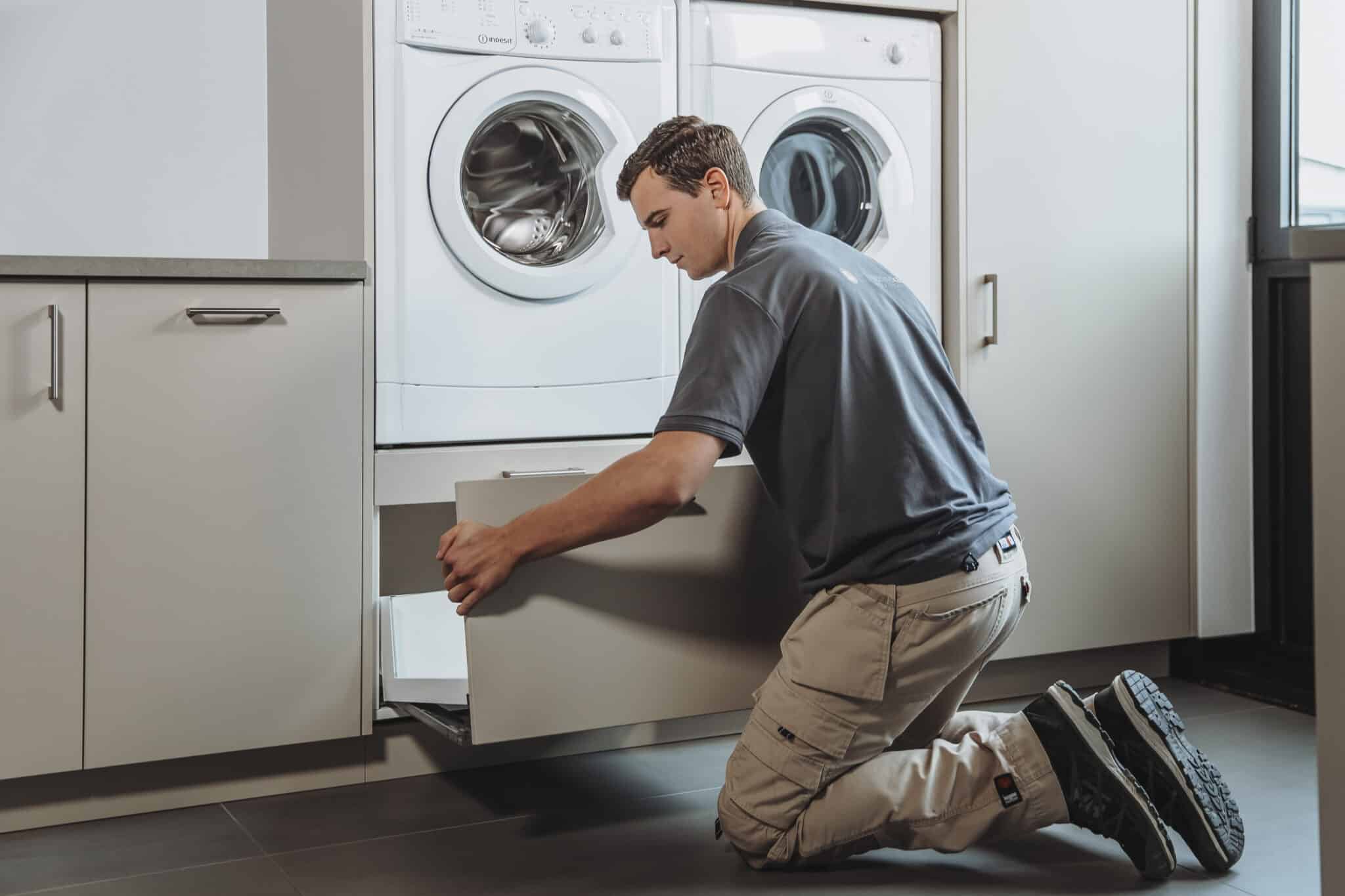 Man die een lade in een wasmachinekast monteert